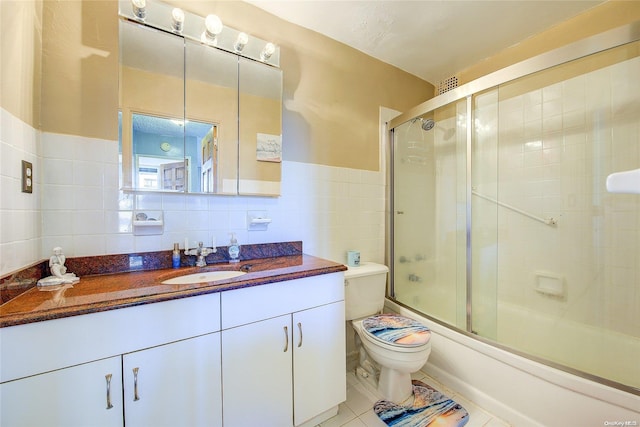 full bathroom with vanity, combined bath / shower with glass door, tile patterned flooring, toilet, and tile walls