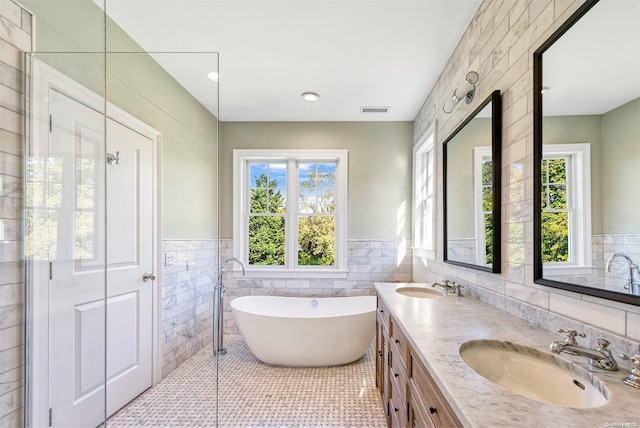 bathroom featuring vanity, a healthy amount of sunlight, and tile walls