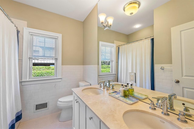 bathroom featuring tile patterned flooring, vanity, toilet, and tile walls