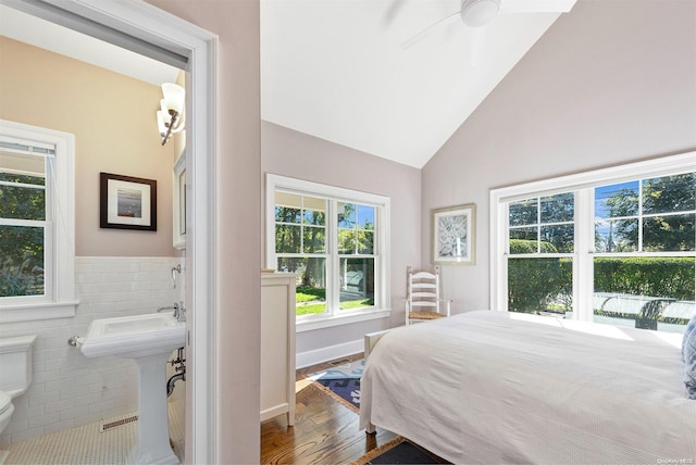 bedroom featuring ensuite bath, ceiling fan, sink, hardwood / wood-style floors, and tile walls