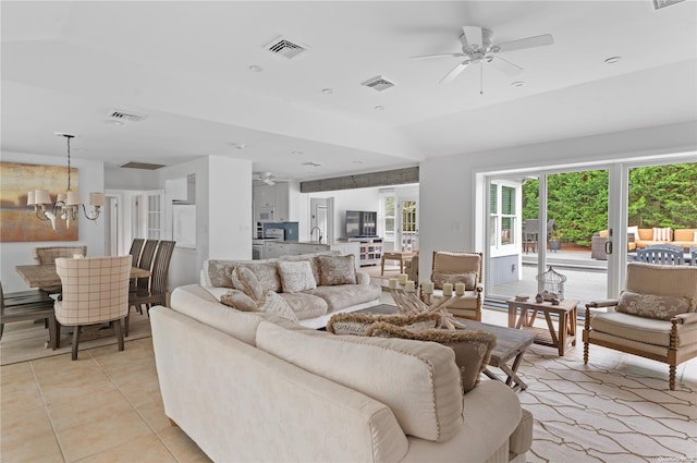 living room with vaulted ceiling, sink, light tile patterned floors, and ceiling fan with notable chandelier