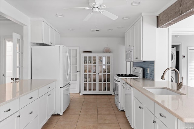 kitchen featuring white cabinetry, sink, ceiling fan, light stone countertops, and white appliances