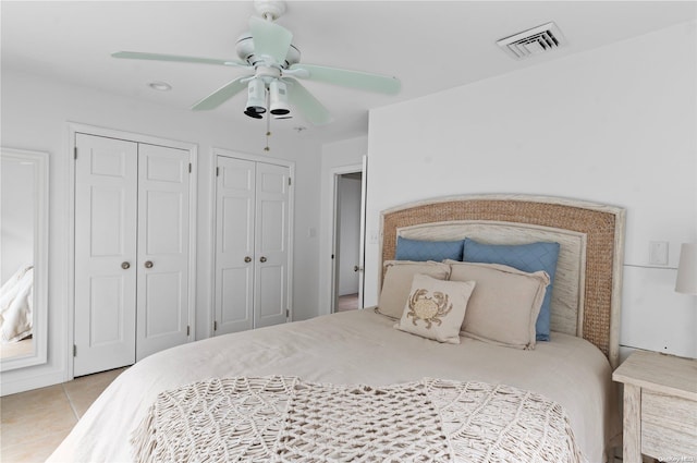 tiled bedroom featuring two closets and ceiling fan