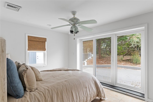 tiled bedroom with ceiling fan, baseboard heating, access to outside, and multiple windows