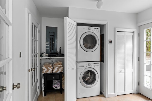 laundry room with stacked washing maching and dryer and light tile patterned floors