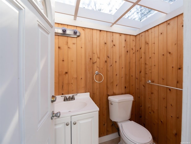 bathroom with vanity, toilet, and wood walls