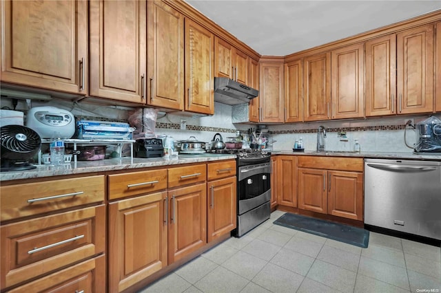 kitchen featuring decorative backsplash, appliances with stainless steel finishes, light stone counters, sink, and light tile patterned floors