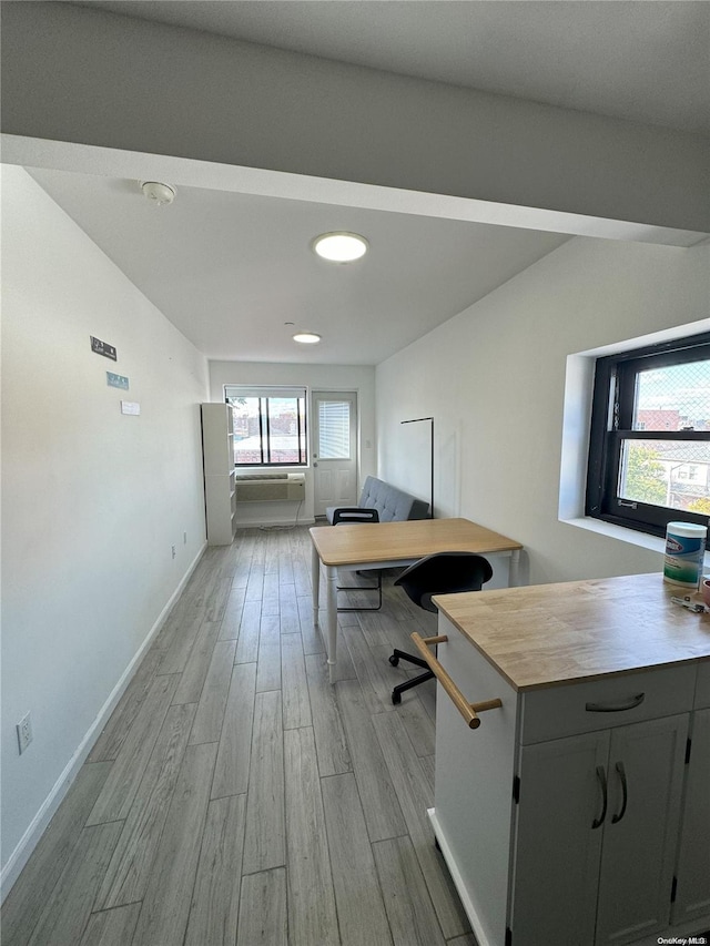 unfurnished office with plenty of natural light, vaulted ceiling, and light wood-type flooring