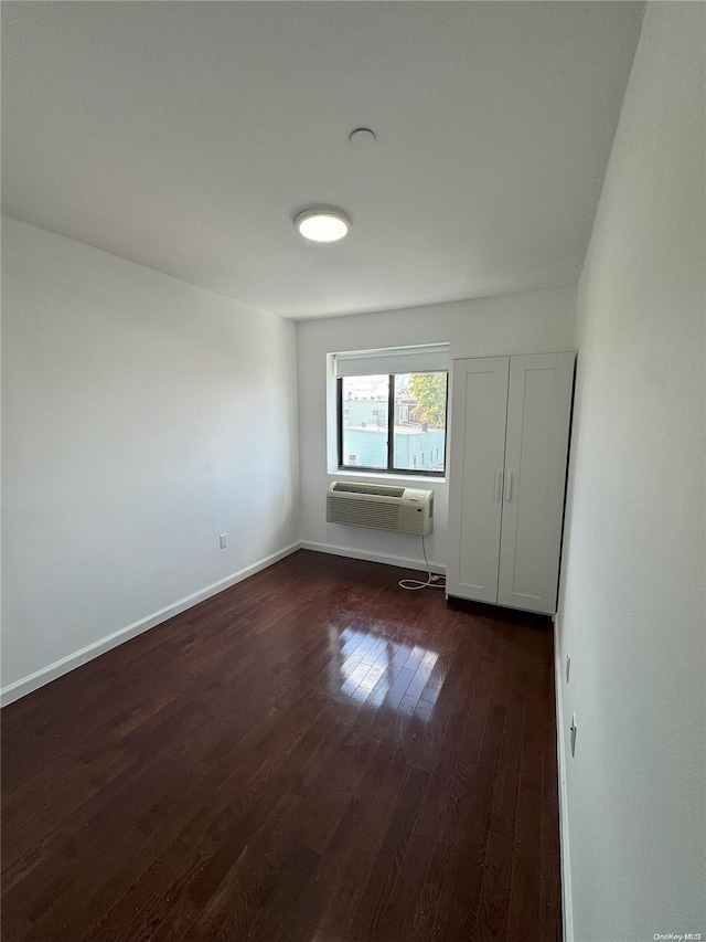 empty room featuring dark hardwood / wood-style flooring and an AC wall unit