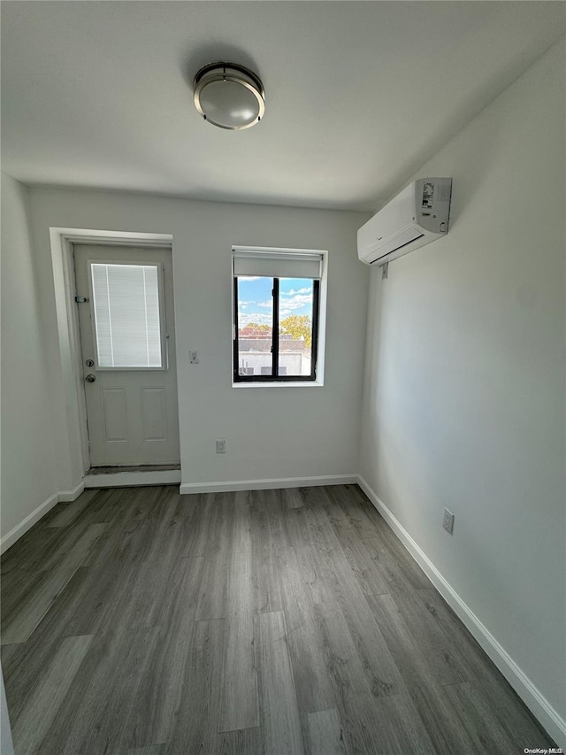 unfurnished dining area with hardwood / wood-style floors and an AC wall unit