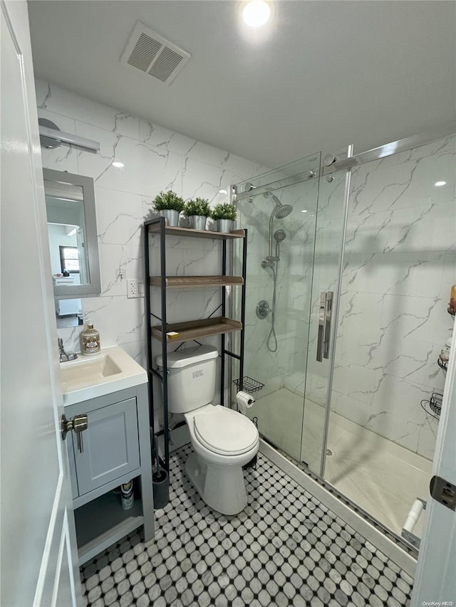 bathroom featuring a shower with door, vanity, and toilet