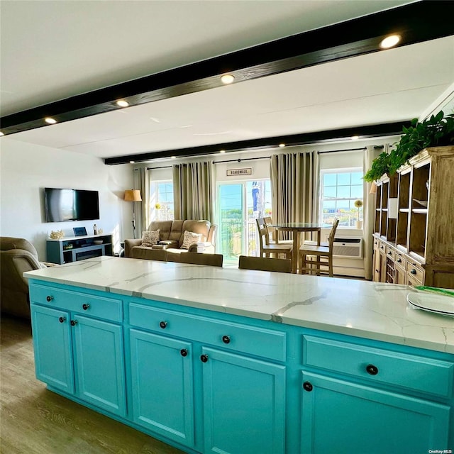 kitchen featuring blue cabinetry, a wealth of natural light, beamed ceiling, and wood-type flooring