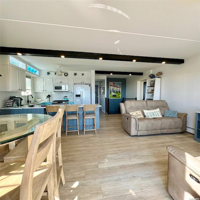 living room featuring beam ceiling, light hardwood / wood-style flooring, and a baseboard heating unit