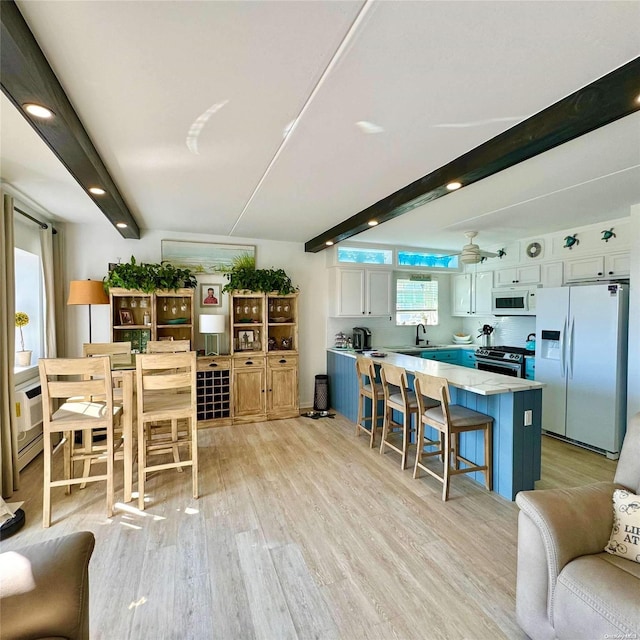 kitchen featuring beamed ceiling, white cabinets, white appliances, and light hardwood / wood-style flooring