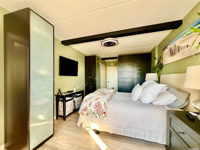 bedroom with beam ceiling and light hardwood / wood-style flooring