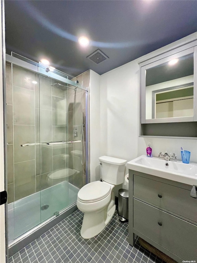 bathroom with tile patterned floors, vanity, toilet, and a shower with shower door