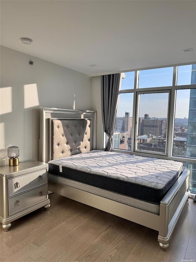 bedroom featuring expansive windows and hardwood / wood-style flooring