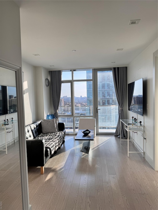 living room featuring plenty of natural light, floor to ceiling windows, and light hardwood / wood-style floors