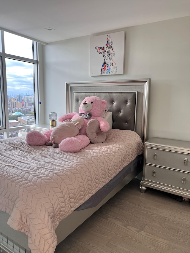 bedroom featuring wood-type flooring and expansive windows