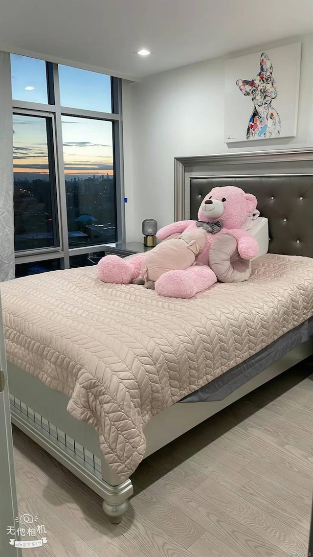 bedroom featuring expansive windows and hardwood / wood-style floors