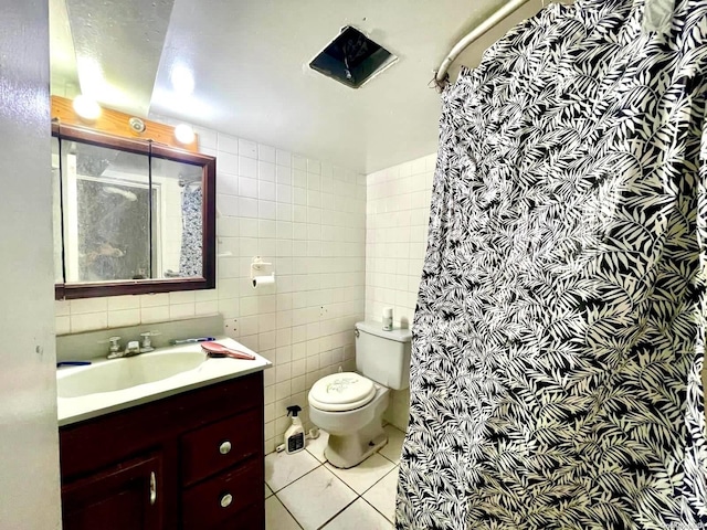 bathroom featuring tile patterned flooring, vanity, toilet, and tile walls