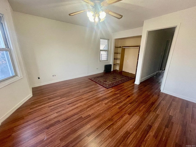 unfurnished living room with ceiling fan, baseboards, and wood finished floors