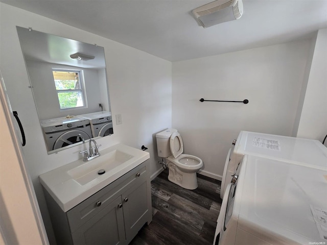 bathroom featuring toilet, vanity, wood-type flooring, and independent washer and dryer