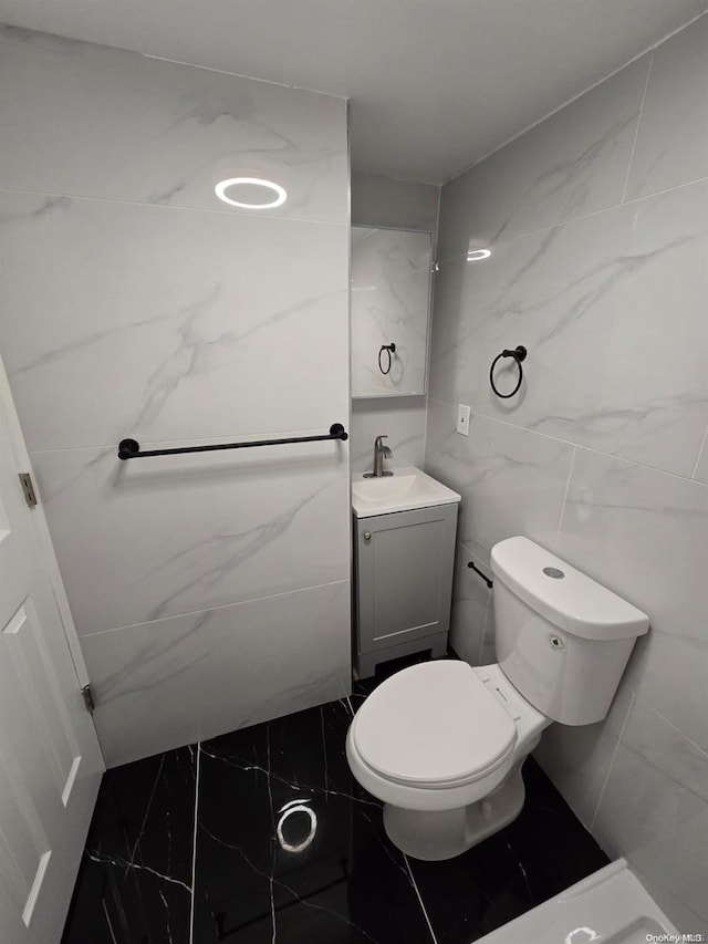 bathroom with vanity, tile walls, and toilet