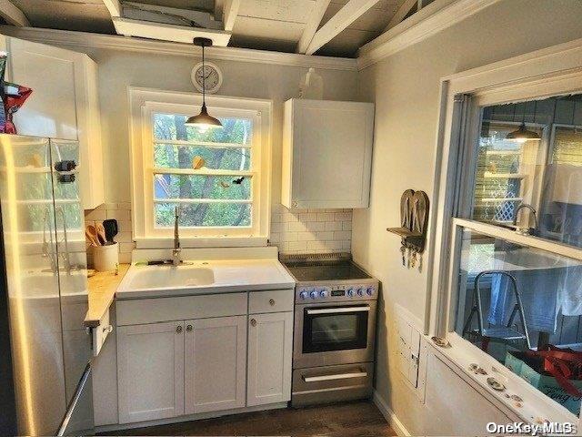 kitchen with sink, hanging light fixtures, stainless steel appliances, tasteful backsplash, and white cabinets