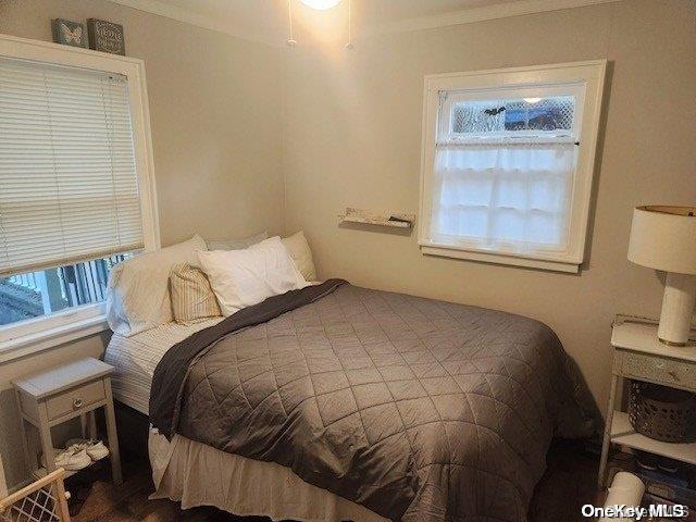 bedroom with wood-type flooring and ornamental molding