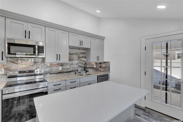 kitchen with tasteful backsplash, stainless steel appliances, vaulted ceiling, sink, and gray cabinets