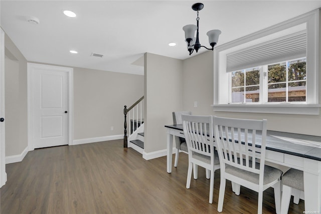 dining space with dark hardwood / wood-style flooring and an inviting chandelier