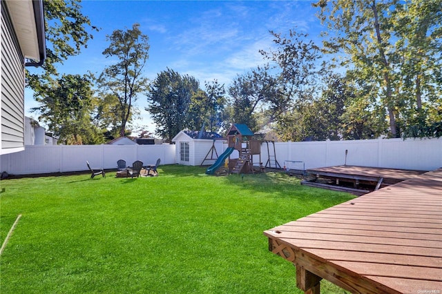 view of yard with a storage unit, a playground, an outdoor fire pit, and a wooden deck