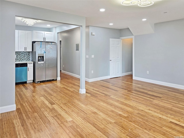 kitchen with decorative backsplash, white cabinetry, stainless steel appliances, and light hardwood / wood-style floors