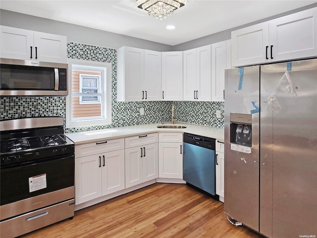 kitchen featuring white cabinets, sink, decorative backsplash, light hardwood / wood-style floors, and stainless steel appliances