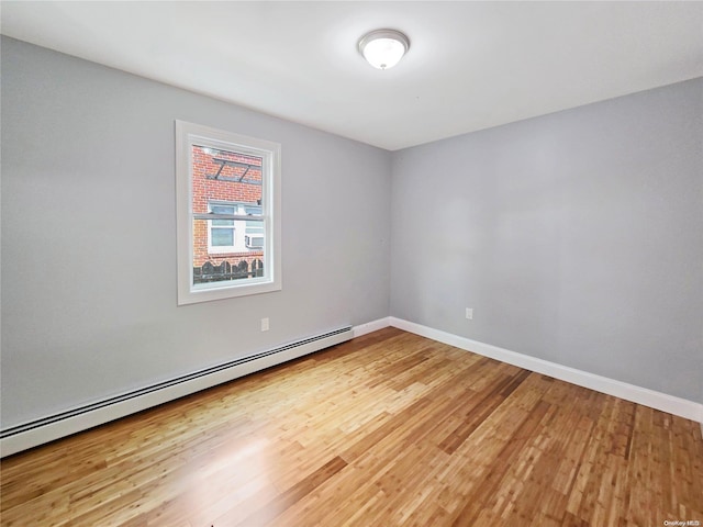 empty room with baseboard heating and wood-type flooring