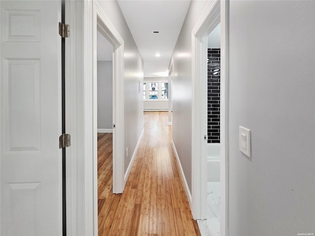 hall with light hardwood / wood-style floors and baseboard heating