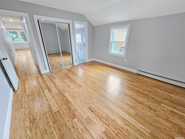 unfurnished bedroom featuring vaulted ceiling, multiple windows, connected bathroom, and light hardwood / wood-style flooring