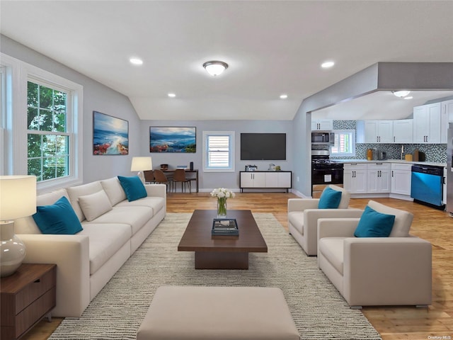 living room with a wealth of natural light, light hardwood / wood-style flooring, and lofted ceiling