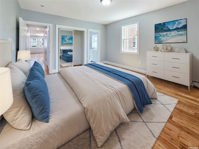 bedroom with ensuite bathroom and light hardwood / wood-style flooring