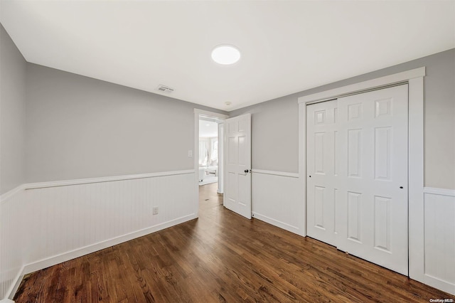 unfurnished bedroom with dark wood-type flooring and a closet