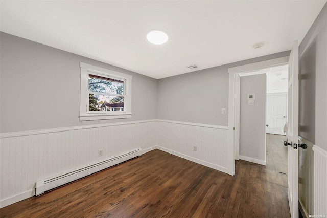 unfurnished room featuring dark hardwood / wood-style floors and a baseboard heating unit