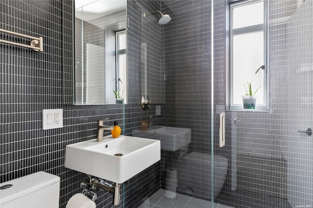 bathroom featuring sink, an enclosed shower, tile walls, and toilet