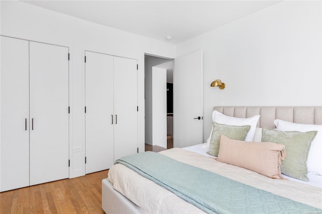 bedroom featuring light wood-type flooring and two closets