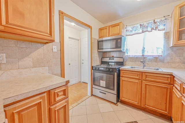 kitchen with appliances with stainless steel finishes, backsplash, light tile patterned floors, and sink