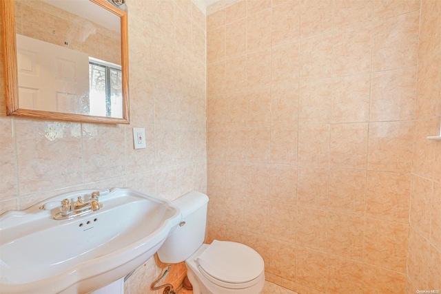 bathroom with toilet, tile walls, and sink