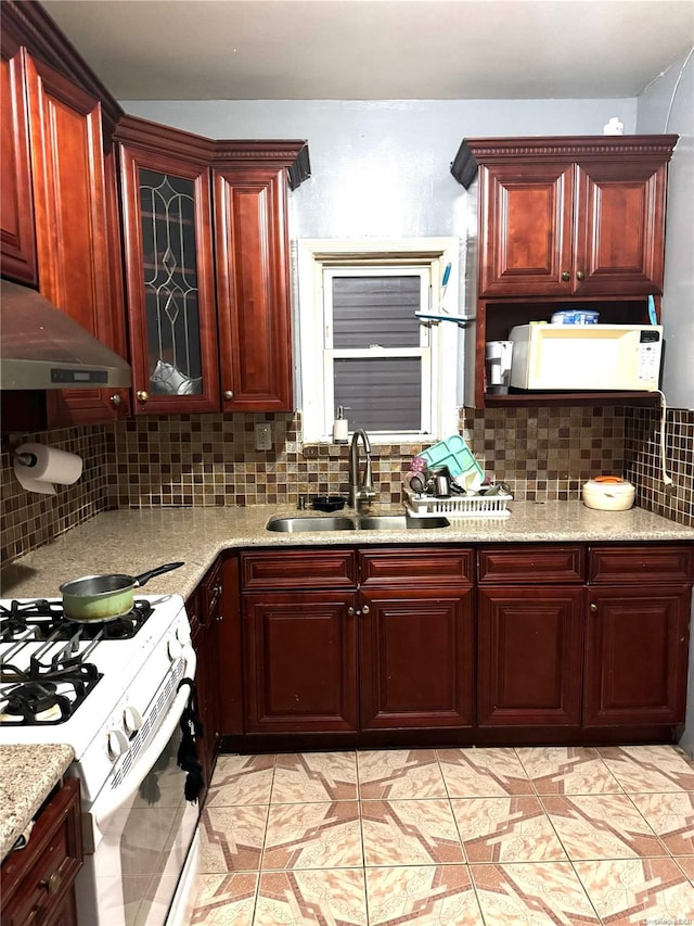 kitchen with decorative backsplash, light stone countertops, white appliances, sink, and range hood