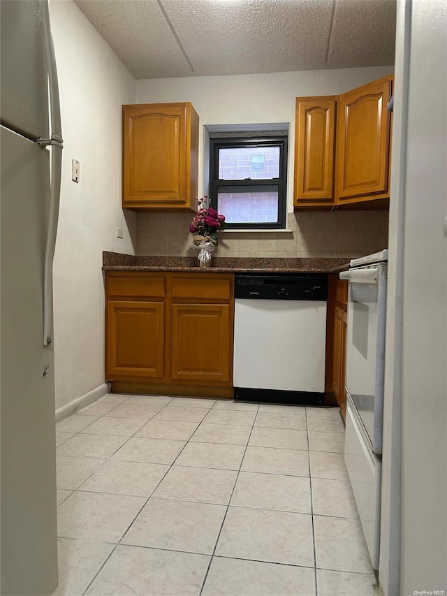 kitchen featuring a textured ceiling, white appliances, backsplash, and light tile patterned flooring