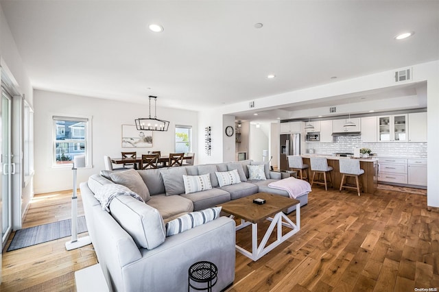 living room with hardwood / wood-style floors, plenty of natural light, and a notable chandelier