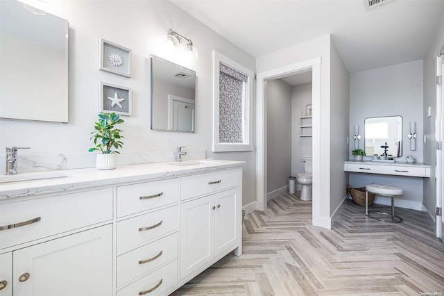 bathroom with vanity, parquet floors, and toilet